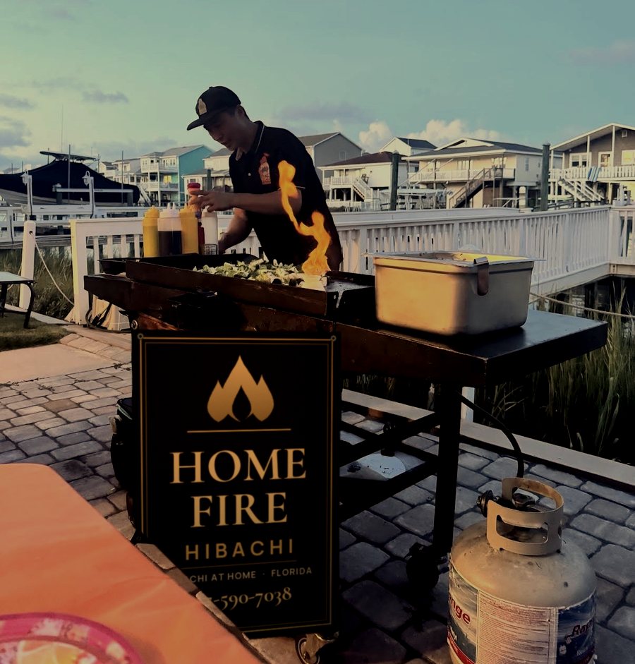 HomeFire Hibachi grill on a waterfront patio as the chef cooks at dusk