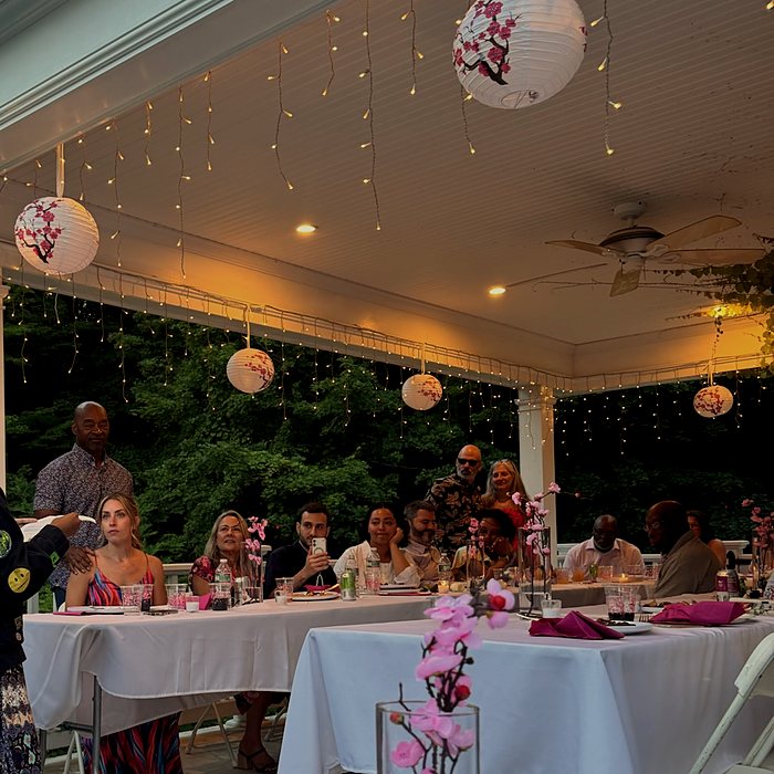 Guests at white-linen tables under paper lanterns and string lights